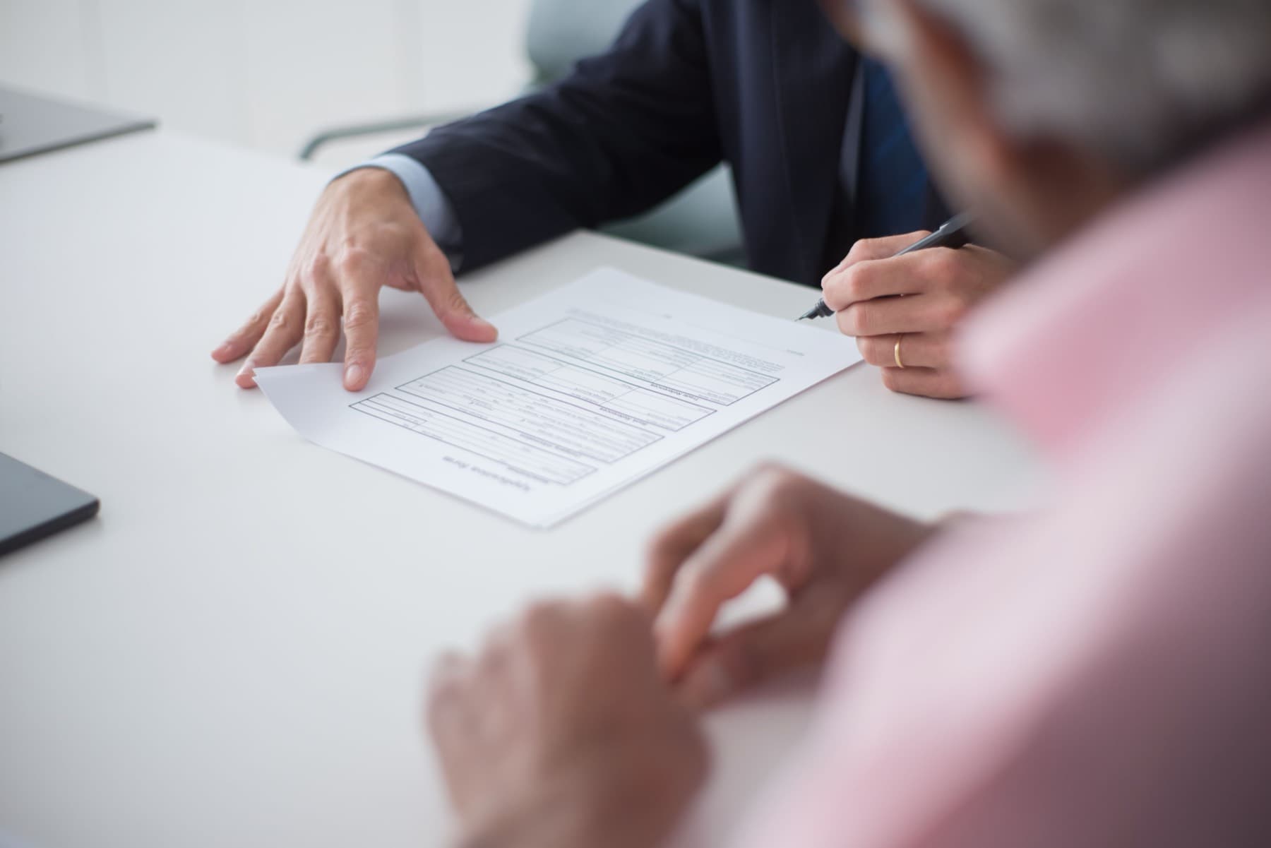 Two people at a desk going through paperwork together, one signing a form.
